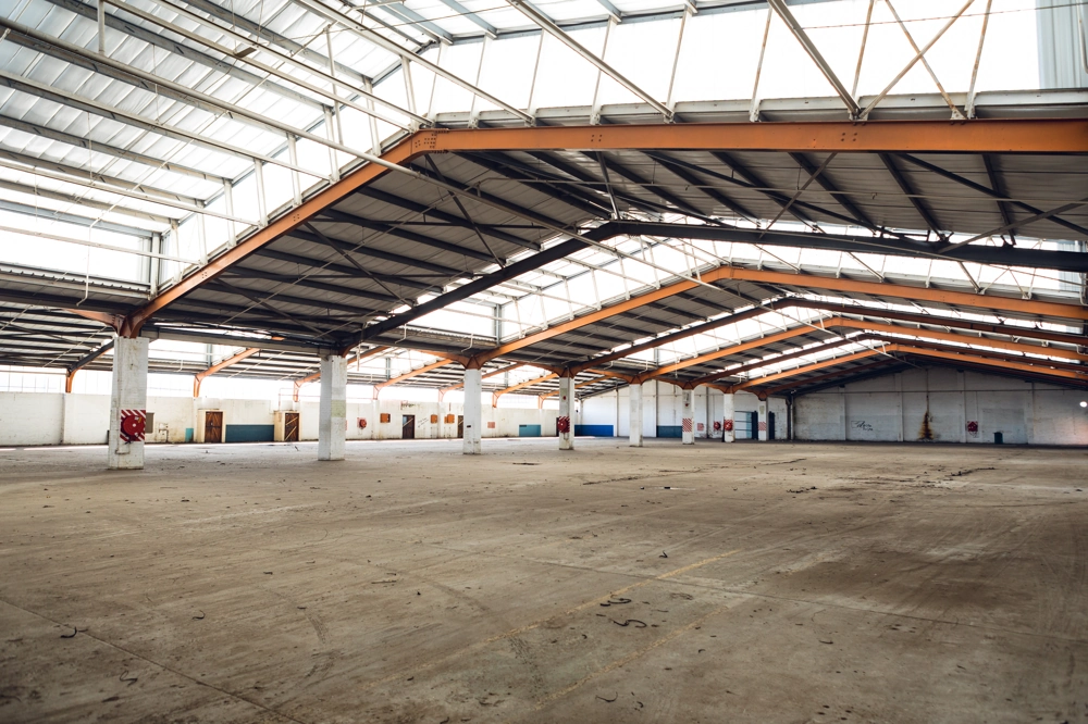 Weite, helle Lagerhalle mit Stahlträgern und Trapezblech-Dach