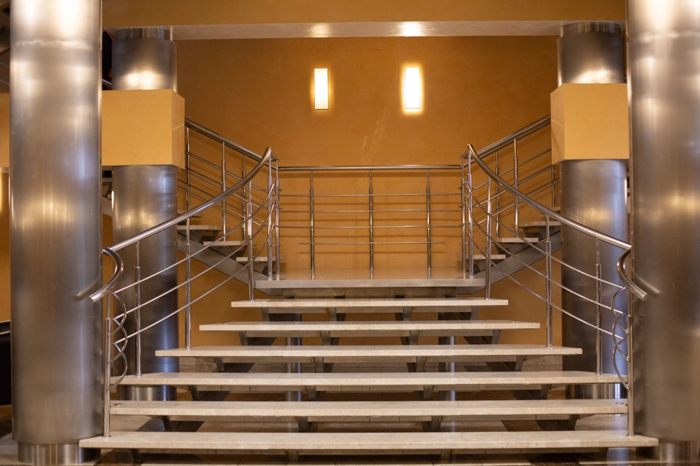 Moderne Metalltreppe mit geschwungenem Edelstahlgeländer im Innenbereich
