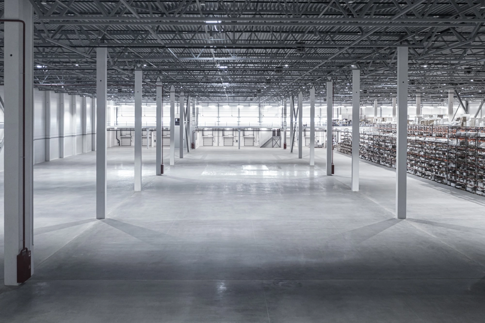 Weite, helle Lagerhalle mit Stahlstützen und Regalsystemen