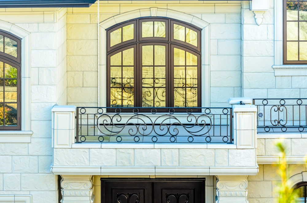 Verziertes Balkongeländer aus Metall mit geschmiedeten Ornamenten an Hausfassade aus Stein
