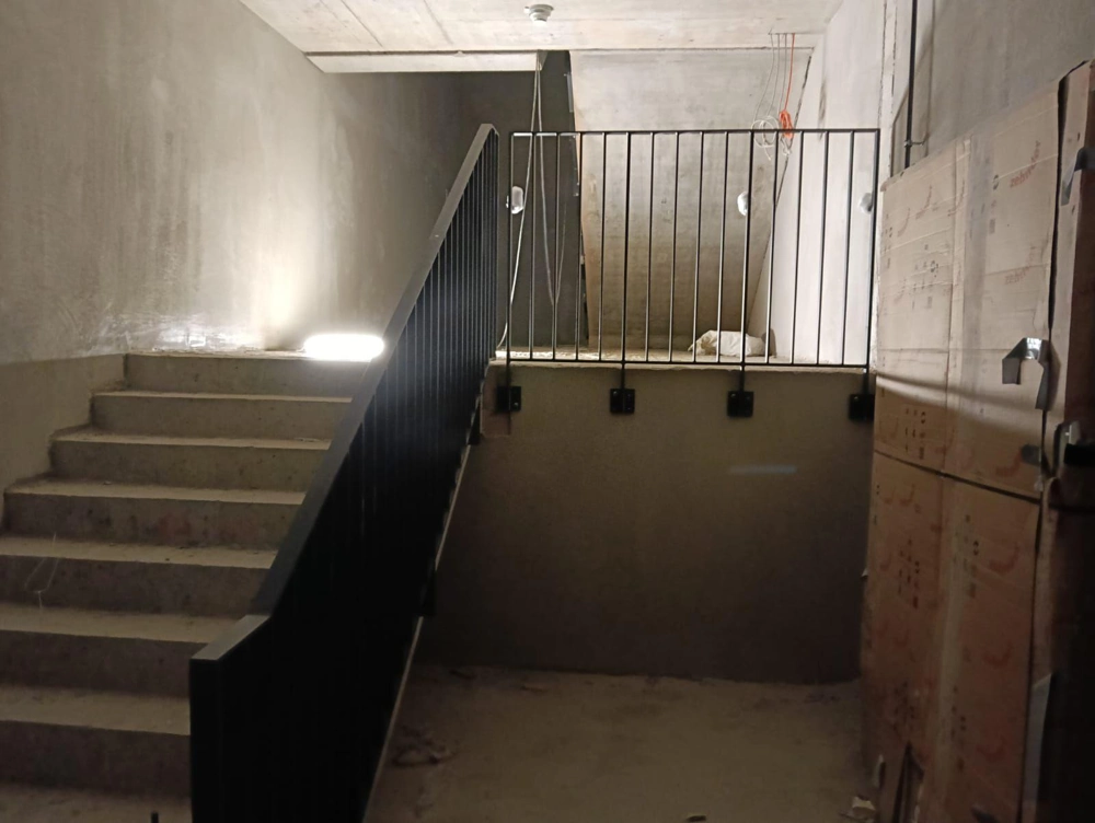 Betontreppe mit schwarzem Treppengeländer aus Metall in Rohbau-Umgebung