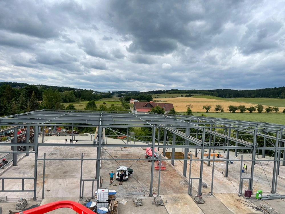 Baustelle im Hallenbau: Stahlunterkonstruktion auf Betonplatte mit Landschaft im Hintergrund