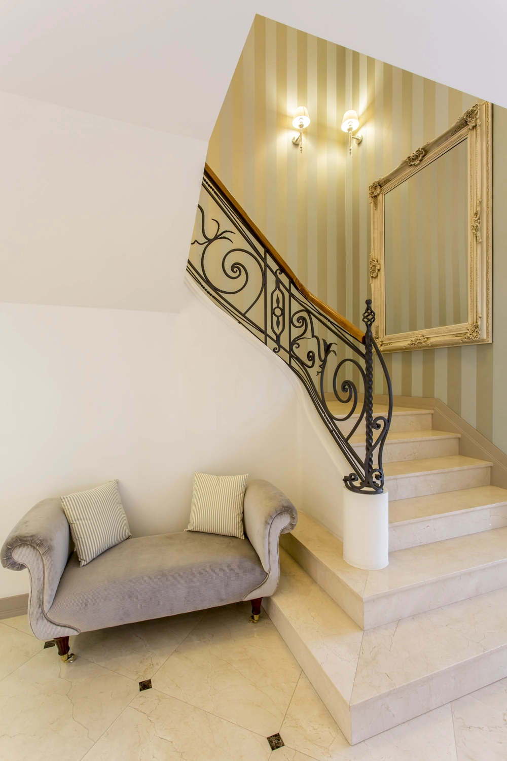 Elegantes Treppengeländer aus geschmiedetem Metall mit Holzhandlauf an heller Marmortreppe in repräsentativem Eingangsbereich
