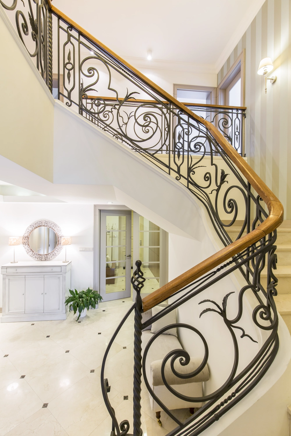 Innenansicht einer eleganten Metalltreppe mit geschwungenem Treppengeländer und Holzhandlauf