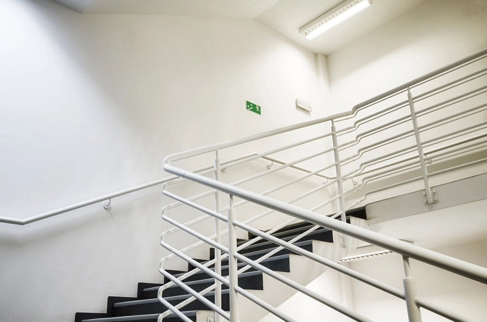 Innenansicht einer Metalltreppe mit weißem Treppengeländer in hellem Treppenhaus