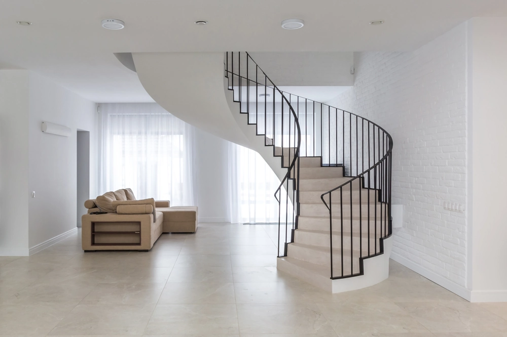 Geschwungene Metalltreppe mit schwarzem Treppengeländer in hellem Wohnraum