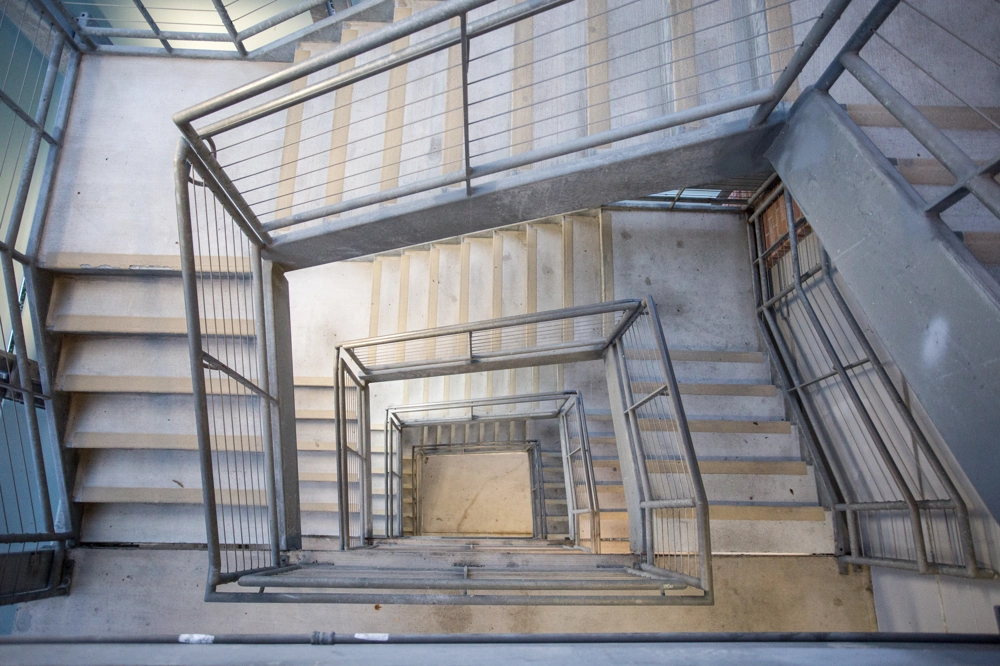 Rechteckige Metalltreppe mit mehreren Etagen und durchgängigem Treppengeländer aus Stahl